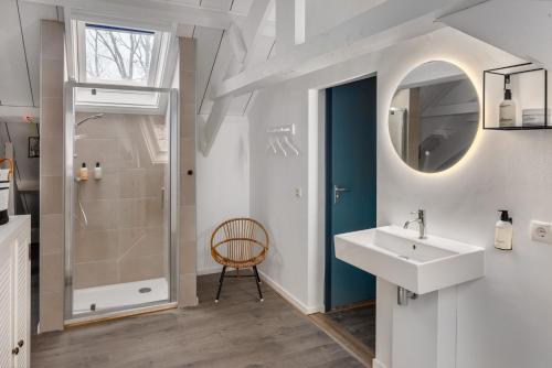 een badkamer met een wastafel en een douche bij Koetshuis Buitenplaats Iepenoord in Oostkapelle