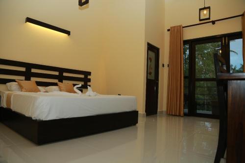 a bedroom with a bed with white sheets and orange pillows at Charly breeze in Ahangama