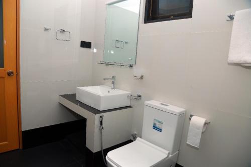 a white bathroom with a sink and a toilet at Charly breeze in Ahangama