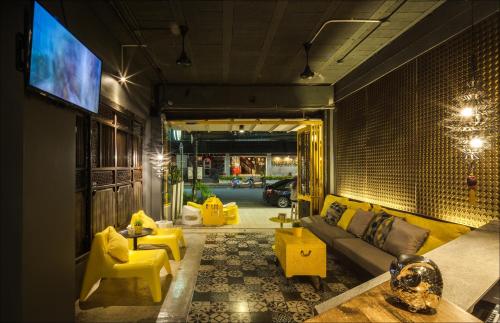 a living room with a couch and yellow chairs at Fulfill Phuket - SHA in Phuket