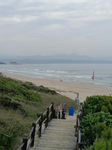 a wooden boardwalk leading to a beach with benches at Wave Echo in Plettenberg Bay