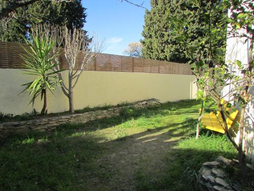 une clôture dans une cour à côté d'un mur dans l'établissement Chambre agréable dans une maison avec un grand lit, à Nîmes