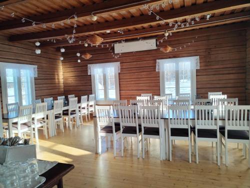 una habitación con hileras de mesas y sillas blancas en Ristijärven Pirtti Cottage Village en Ristijärvi