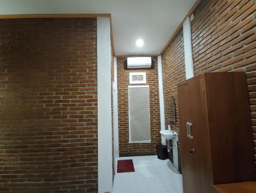 a bathroom with a brick wall and a mirror at Genthong Homestay in Borobudur