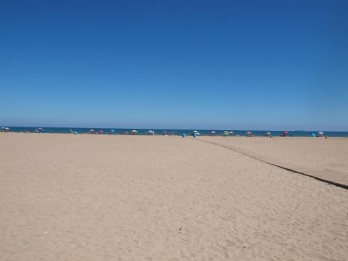 una playa de arena con un grupo de personas en el océano en Malvarrosa Las Arenas Access, en Valencia