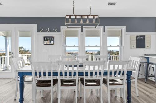 a dining room with a blue table and white chairs at Genuine Holden Beach Ocean front with private pool and great beach views in Holden Beach