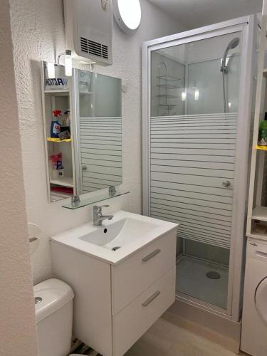 une salle de bain blanche avec un lavabo et une douche dans l'établissement Studio meuble bord de mer, à Bormes-les-Mimosas