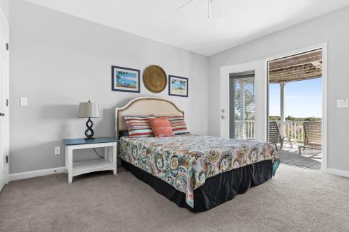 a bedroom with a bed and a table and a balcony at Genuine Holden Beach Ocean front with private pool and great beach views in Holden Beach