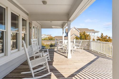 a porch with chairs and tables on a house at Genuine Holden Beach Ocean front with private pool and great beach views in Holden Beach
