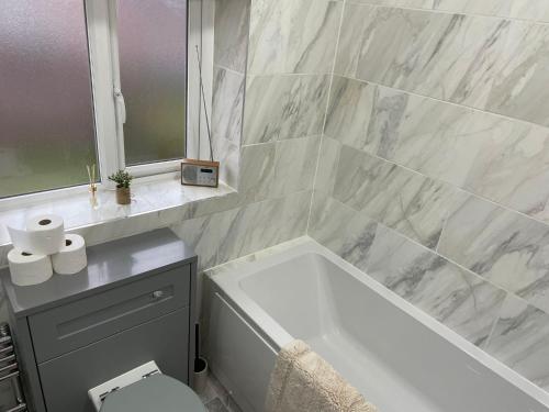 a bathroom with a tub and a toilet and a sink at Beautiful 3-Bed House in Romford in Romford