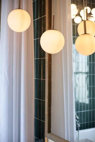 two lights hanging over a mirror in a bathroom at Secret Garden Studio w/ Hot Tub: Near Forsyth Park in Savannah