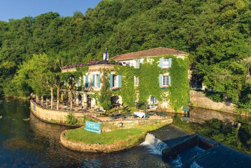 a house that has a boat in the water at Moulin de l'Abbaye - Relais et Chateaux in Brantôme