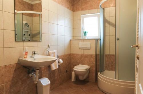 a bathroom with a sink and a toilet and a shower at Apartman Oskar 1 in Kupres