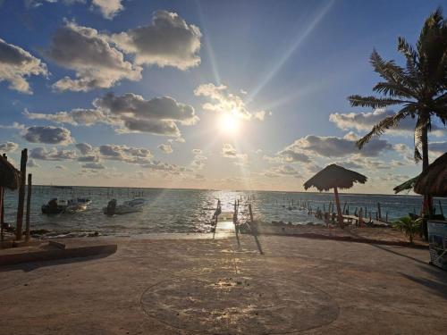 una playa con barcos en el agua y el sol en Hidden Jems Mahahual Hotel & Hostel en Mahahual