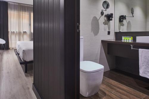 a bathroom with a toilet and a sink and a bed at Silken Gran Teatro in Burgos