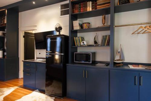 a kitchen with blue cabinets and a black refrigerator at Intimate Library Studio - Minutes to Forsyth Park in Savannah