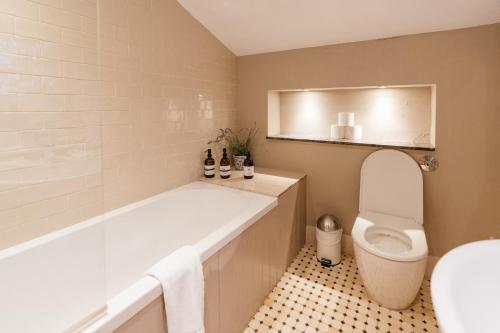 a bathroom with a tub and a toilet and a sink at Retreat East in Ipswich