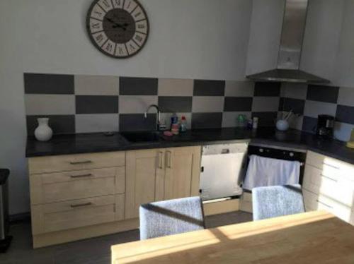 a kitchen with a sink and a clock on the wall at Maison accueillante à Bléré avec cheminée et terrasse in Bléré