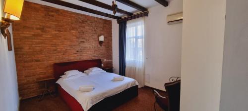 1 dormitorio con 1 cama con pared de ladrillo en Topaz Boutique, en Cluj-Napoca