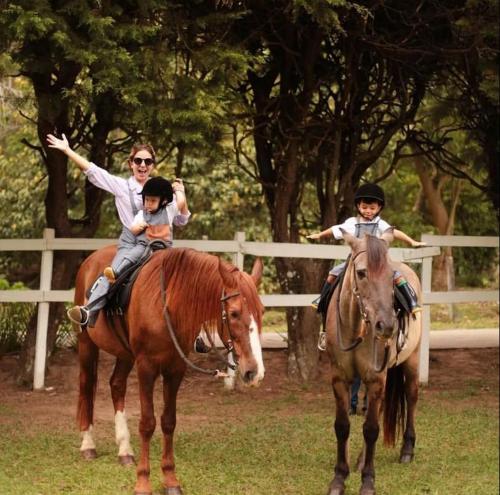 Eine Frau und zwei Kinder reiten auf Pferden in der Unterkunft Locanda Bela Vista in Itaipava