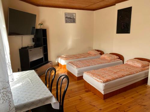 a room with three beds and a flat screen tv at Pokoje Zielonka in Zielonka