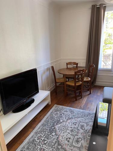 Il comprend un salon doté d'une table et d'une télévision à écran plat. dans l'établissement Magnifique appartement au centre de Montrouge, à Montrouge