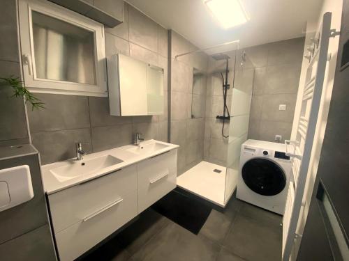 ein Badezimmer mit einem Waschbecken und einer Waschmaschine in der Unterkunft Maison 4 chambres au calme beau jardin et studio in Cagny
