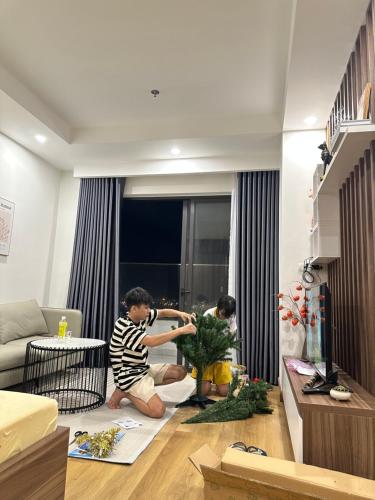zwei Personen im Wohnzimmer, die mit einer Pflanze spielen in der Unterkunft Sam's House in Quy Nhon
