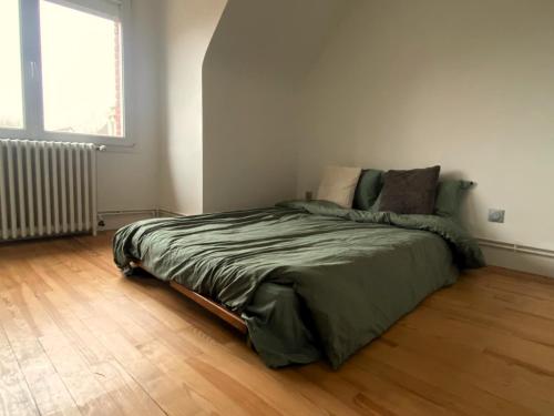 Bett in einem Zimmer mit Holzboden in der Unterkunft Maison 4 chambres au calme beau jardin et studio in Cagny