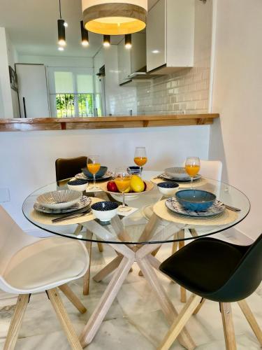 a glass table with four chairs and wine glasses at 2 Bed Ground Floor Apartment With Pool & Parking in Mijas Costa