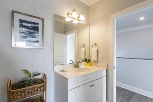 a bathroom with a sink and a mirror at Kind Of A Big Deal Brunswick Vacation Rentals Private home with pool and elevator in Holden Beach