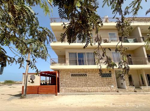 a building on the beach with a tree at Ocean Breeze 9 in Sal Rei