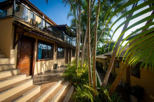 una casa con un porche con palmeras al lado en Hotel Barra da Lagoa by Latitud Hoteles en Búzios
