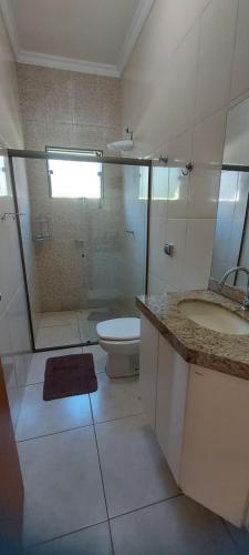 uma casa de banho com um chuveiro, um WC e um lavatório. em Chácara Tranquila Pouso Alegre em Pouso Alegre