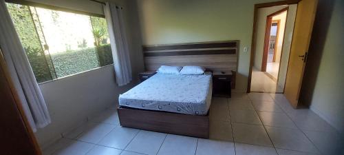 um quarto com uma cama e uma grande janela em Chácara Tranquila Pouso Alegre em Pouso Alegre