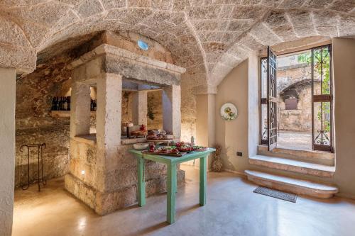 a stone kitchen with a green table in a room at Masseria Brigantino in Torre Canne