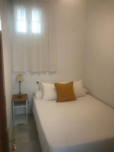 1 dormitorio con cama blanca y ventana en Apartamento en el centro, en Sanlúcar de Barrameda