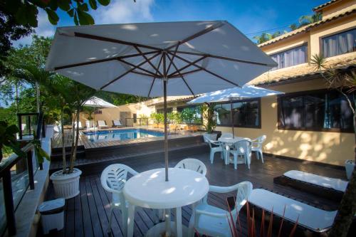 a patio with a table and chairs and an umbrella at Hotel Barra da Lagoa by Latitud Hoteles in Búzios