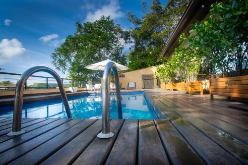 a swimming pool with an umbrella on a wooden deck at Hotel Barra da Lagoa by Latitud Hoteles in Búzios