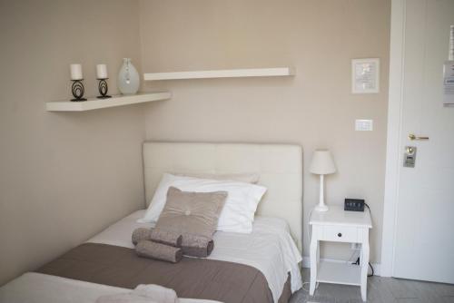 a white bedroom with a bed and a night stand at Your House Rooms in Genova