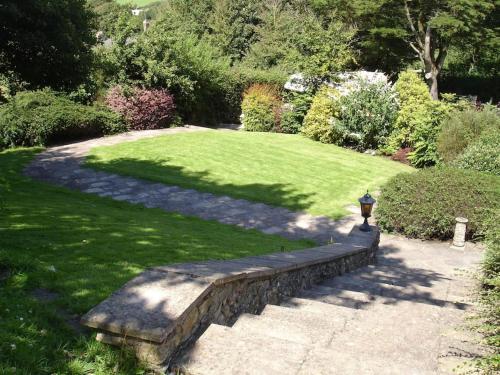 a garden with a stone wall and a grass yard at Spring Barn at Bolberry Court in Hope-Cove