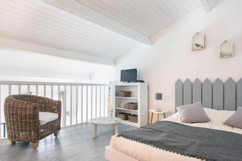 um quarto branco com uma cama e uma cadeira em Les Mouettes Appartement cosy avec piscine em Saint-Martin-de-Ré