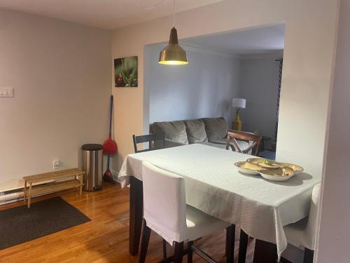 a dining room with a white table and chairs at Appartement près du Métro in Laval
