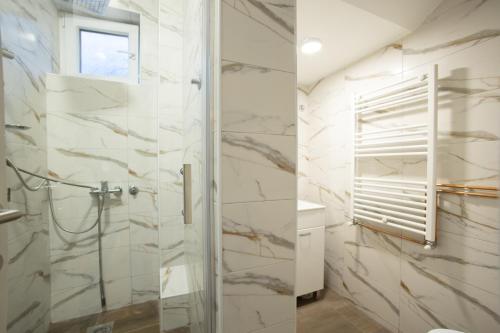 a bathroom with a shower with marble walls and a window at V & V Studio Apartments 2 in Niš