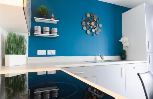 a blue kitchen with a sink and a blue wall at Stylish House with Private parking in Glasgow