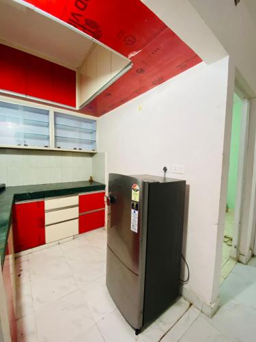 Kuchnia wyposażona jest w czerwono-białe szafki i lodówkę. w obiekcie NapStayz 5.0 w mieście Lucknow