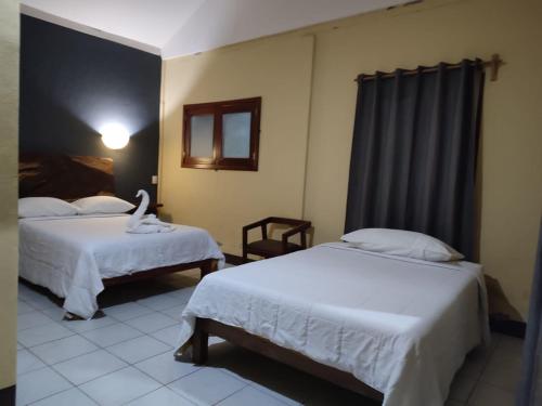um quarto de hotel com duas camas e uma janela em Finca San Antonio em Pluma Hidalgo