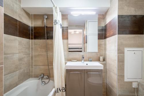 y baño con lavabo, bañera y ducha. en Appartement Océanis avec Piscine proche du port, en Saint-Martin-de-Ré