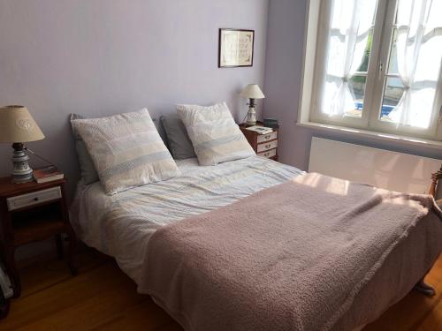 een bed in een slaapkamer met 2 lampen en een raam bij villa stella in Ault