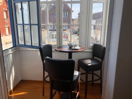 een tafel en stoelen in een kamer met ramen bij villa stella in Ault